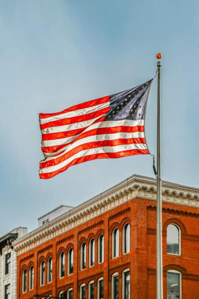 A large American flag flying from a tall outdoor flagpole, sized to the pole height