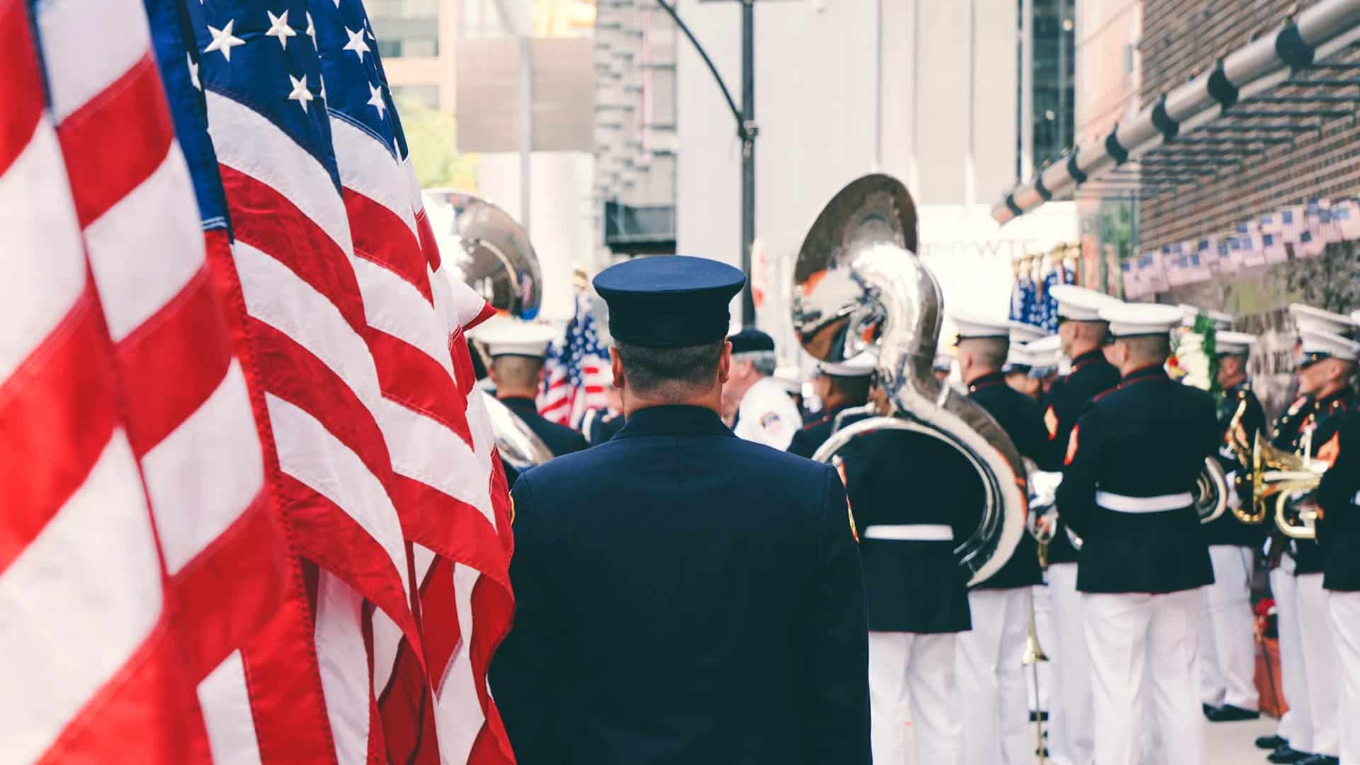 Marine Corps band and color guard with American flags at a ceremony