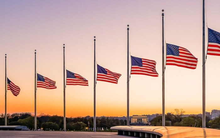 A row of American flags flying at half-staff at sunset