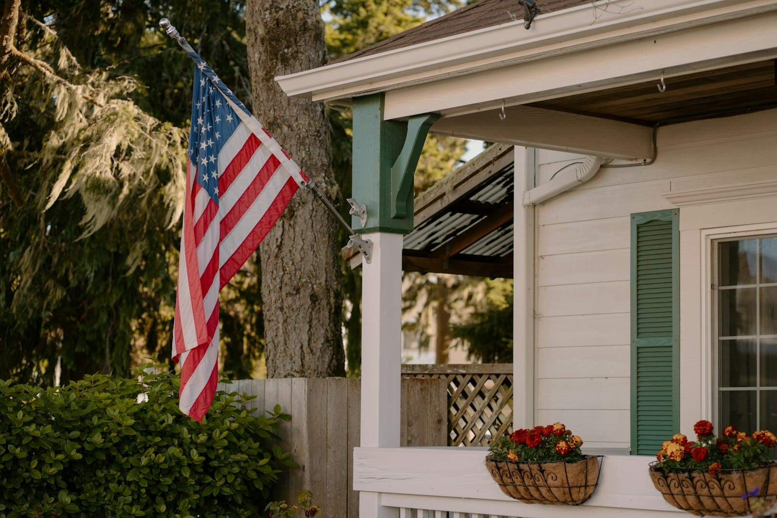 An American flag on an angled wall bracket at a house porch, a display that cannot be lowered to half-staff