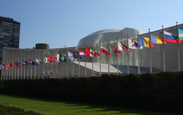 Member state flags on identical poles at identical height along the front of the United Nations General Assembly building on First Avenue in New York