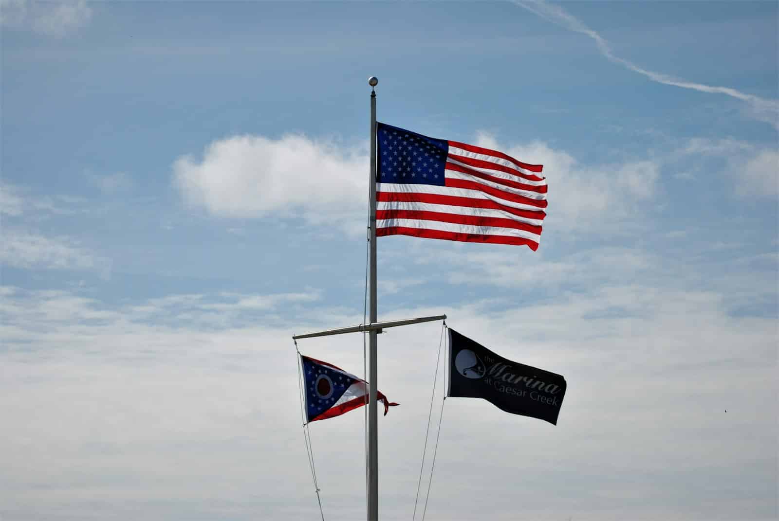 The American flag at the peak of a single flagpole, with the Ohio state flag and an organizational flag below it on the same halyard